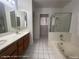 Bathroom featuring a double vanity, tub and shower, and white tile flooring at 6512 Sterling Springs Pkwy, Las Vegas, NV 89108