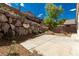 Backyard features a rock wall, concrete patio, and desert landscaping at 71 Blaven Dr, Henderson, NV 89002