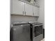 Laundry room equipped with gray front-loading washer and dryer, plus upper cabinets at 8668 Marcana St, Las Vegas, NV 89166