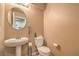 Tan half bath with round mirror, pedestal sink, and standard toilet at 978 Valetta Flat Ave, Las Vegas, NV 89183