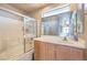 Bathroom with white tile, glass shower door, oak vanity, and good natural light at 978 Valetta Flat Ave, Las Vegas, NV 89183