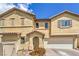 Close-up of a tan, two-story home featuring a two-car garage and desert-style landscaping at 978 Valetta Flat Ave, Las Vegas, NV 89183