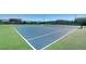 Brightly colored tennis court with blue and green surfaces, surrounded by a dark fence and nearby homes in the background at 11356 Belmont Lake Dr # 103, Las Vegas, NV 89135
