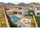 Aerial view featuring a modern backyard with a pool, spa, firepit and lounge chairs with mountain views at 11943 Rockview Point St, Las Vegas, NV 89138