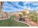 Beautiful backyard featuring artificial turf, pond, outdoor kitchen and mature landscaping at 1324 Spice Ridge Ct, Henderson, NV 89012