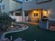 Backyard at dusk with an outdoor kitchen, pond, patio, and artificial turf at 1324 Spice Ridge Ct, Henderson, NV 89012