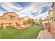 Expansive backyard with artificial turf, outdoor kitchen, mature landscaping, pond and seating area at 1324 Spice Ridge Ct, Henderson, NV 89012