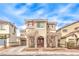 Charming two-story home with red shutters and an arched entrance, set under a bright blue, partly cloudy sky at 1324 Spice Ridge Ct, Henderson, NV 89012