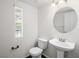 Half bathroom includes sleek toilet, window, and a sink with bronze fixtures at 16 Goldleaf Falls Ave, North Las Vegas, NV 89031