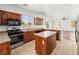 Kitchen showcases wood cabinets, speckled countertops, tile floors, island, and stainless steel oven at 16 Goldleaf Falls Ave, North Las Vegas, NV 89031
