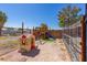 View of fenced backyard with playhouse and wooden playset for Gathering enjoyment at 208 W Alma St, Overton, NV 89040