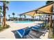 Enjoy this outdoor community pool with palm trees and blue lounge chairs under a shade structure on a sunny day at 2845 Copper Wind Ln # 4, Las Vegas, NV 89183