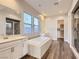 Spa-like bathroom featuring a soaking tub, dual vanities, a glass-enclosed shower, and wood-look floors at 3008 Barrett Springs Ave, Henderson, NV 89044