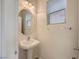 Bathroom features a pedestal sink, a round mirror, and a window at 4045 Oliver Sagebrush Dr, Las Vegas, NV 89122
