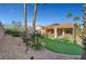 Landscaped backyard featuring a covered patio, artificial turf area, palm trees, and a gravel area at 4379 Bella Cascada St, Las Vegas, NV 89135