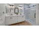 Modern bathroom featuring double sinks, round mirrors, and a glass-enclosed shower with decorative tile at 4379 Bella Cascada St, Las Vegas, NV 89135