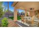 Covered patio featuring a glass top table with six chairs, palm trees, and views of the backyard at 4379 Bella Cascada St, Las Vegas, NV 89135