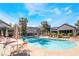 Community pool area featuring a large pool, lounge chairs, tables with umbrellas, and lush landscaping at 5710 E Tropicana Ave # 2122, Las Vegas, NV 89122