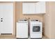 Bright laundry room with washer, dryer, storage cabinets, and white door at 6961 Emerald Springs Ln, Las Vegas, NV 89113