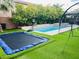 Resort-style backyard with a sparkling pool, trampoline, and lush landscaping provides outdoor enjoyment at 7109 Rancho De Taos, Las Vegas, NV 89130