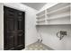 Clean laundry room with a patterned floor, a black door, and open shelving for storage at 7413 Red Eagle St, Las Vegas, NV 89131