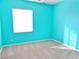 Empty bedroom boasts aqua painted walls, neutral carpet, white trim and a window at 1004 Windy Ferrell Ave, North Las Vegas, NV 89081