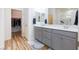 Bright bathroom featuring double vanity, grey cabinets, white countertops, and walk-in closet access at 10095 Ferton Lake Ave, Las Vegas, NV 89178