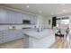 Stylish kitchen with grey cabinets, granite counters, an island, and a view to the dining area at 10095 Ferton Lake Ave, Las Vegas, NV 89178