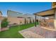 Lush backyard with manicured lawn, mature trees, brick-paved patio, and outdoor dining set for entertaining at 10251 Tiger Milkweed St, Las Vegas, NV 89141