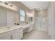 Bathroom featuring dual sinks, white cabinets, and a separate glass-enclosed shower at 10251 Tiger Milkweed St, Las Vegas, NV 89141