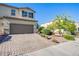 A well-kept home featuring a large two-car garage, a brick driveway, and well-maintained landscaping at 104 Pollentia Ave, North Las Vegas, NV 89084