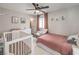 Cozy bedroom featuring a crib, white furniture, ceiling fan, and desert-themed decor for a warm, inviting atmosphere at 11143 Castellane Dr, Las Vegas, NV 89141
