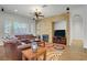 Bright living room with stone fireplace, ceiling fan, and large windows with wooden shutters, offering comfort and style at 11369 Rancho Villa Verde Pl, Las Vegas, NV 89138