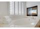 Bright main bathroom featuring a soaking tub, shuttered window, and gold fixtures, providing a luxurious and relaxing experience at 11369 Rancho Villa Verde Pl, Las Vegas, NV 89138
