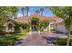 Charming home features a tiled roof, lush landscaping, and a paved driveway leading to the attached garage at 2209 Glenbrook Way, Las Vegas, NV 89117