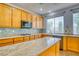 Close up of kitchen island with marble countertops, tile backsplash, and wooden cabinets at 2383 Rainswept Ave, Henderson, NV 89052