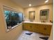 Bathroom with double sinks, bright lighting, and a window providing natural light and a view of outdoor greenery at 2484 Domingo St, Las Vegas, NV 89121