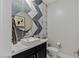Stylish powder room features unique geometric tile wall, round mirror and floating sink at 2518 Veronella St, Henderson, NV 89044