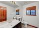 Bright bathroom featuring a white sink, toilet, decorative wood door, and a large window for natural light at 2771 S Buffalo Dr, Las Vegas, NV 89117