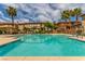 Community pool with multiple lounge chairs next to well maintained townhome buildings and bright blue sky at 3845 Wiggins Bay St # 202, Las Vegas, NV 89129