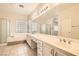 Bathroom featuring double sinks, a large mirror, walk-in shower, and a soaking tub beneath a window at 427 Rhythm St, Henderson, NV 89074