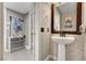Stylish powder room featuring a pedestal sink, decorative mirror, and modern wall tiles at 506 Chestnut View Pl, Henderson, NV 89052