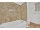 Bathroom featuring tiled tub with shower, neutral wall colors, and window at 5162 Somerset Dr, Las Vegas, NV 89120