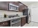 Charming kitchen featuring granite counters, stainless steel appliances, tile floor, and dark wood cabinets at 6731 Sumatra St, Las Vegas, NV 89166