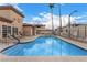 Community pool with lounge seating surrounded by a safety fence and mature palm trees at 6901 Cobre Azul Ave # 202, Las Vegas, NV 89108