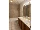 Well lit bathroom featuring dual sinks, wood cabinets, and a shower at 7650 Butterscotch Ct, Las Vegas, NV 89131