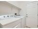 Clean, well-lit laundry area featuring a washer, dryer, shelving, and a door at 841 Colina Alta Pl, Las Vegas, NV 89138