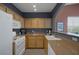 Modern kitchen featuring wooden cabinetry, white appliances, and a convenient breakfast bar at 10001 Peace Way # 2351, Las Vegas, NV 89147