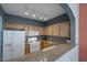 Well-lit kitchen with white appliances, wood cabinets and bar counter overlooking an adjacent room at 10001 Peace Way # 2351, Las Vegas, NV 89147