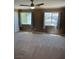 Spacious bedroom with neutral carpeting, a ceiling fan, and windows that provide views of the surrounding neighborhood at 10974 Fintry Hills St, Las Vegas, NV 89141